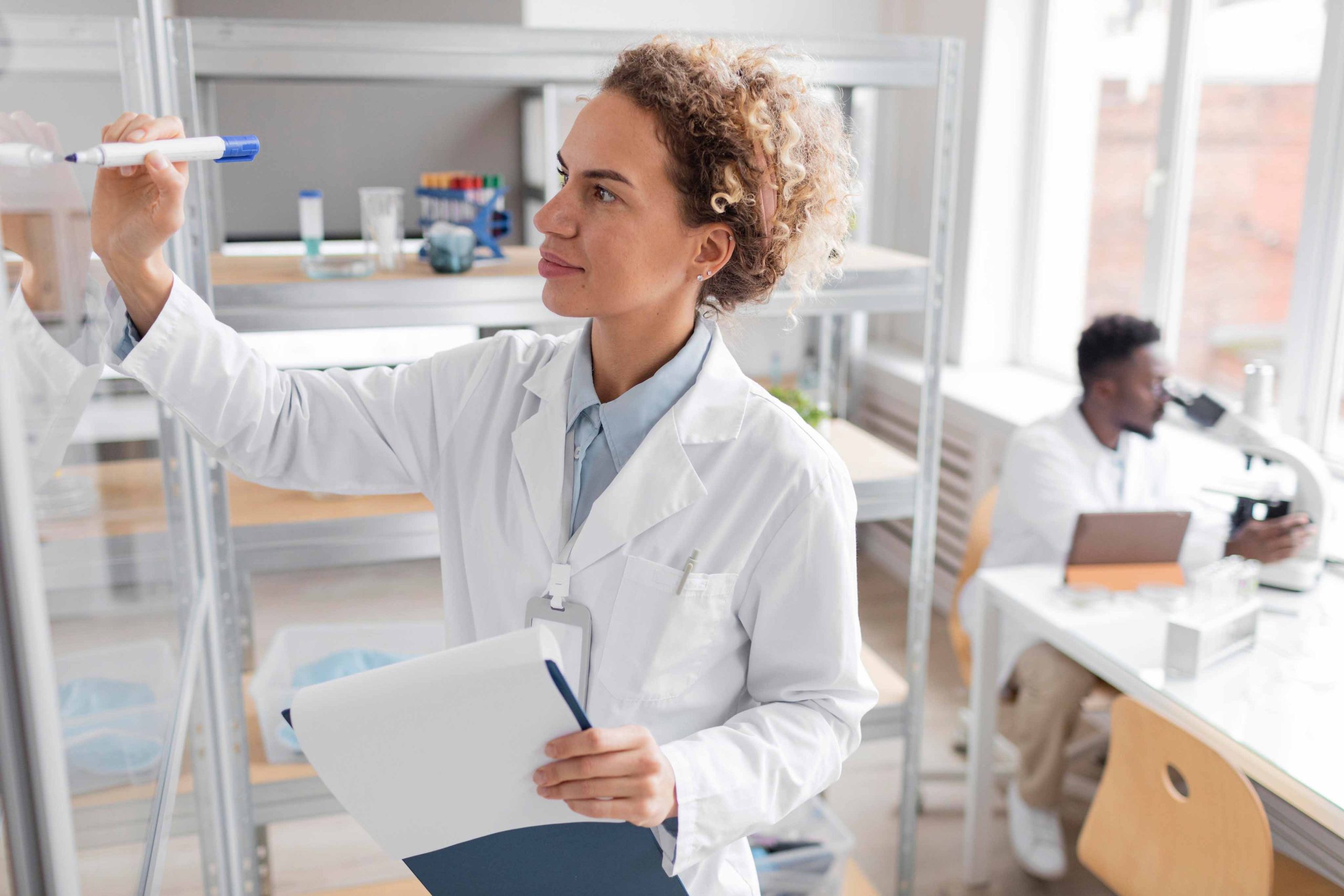 Mujer científica escribiendo en una pizarra en un laboratorio.